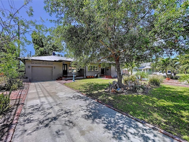 6920 Bougainvilla Ave S, Saint Petersburg, FL 33707 - view of front facade with stucco siding, metal roof, a front lawn, an attached garage, and concrete driveway