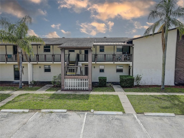 8440 Old Post Rd Unit 104, Port Richey, FL 34668 - view of front facade featuring stucco siding, uncovered parking, a front lawn, stairs, and a balcony