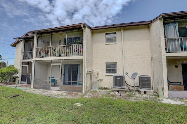 8440 Old Post Rd Unit 104, Port Richey, FL 34668 - back of property featuring a sunroom, stucco siding, a balcony, and a lawn