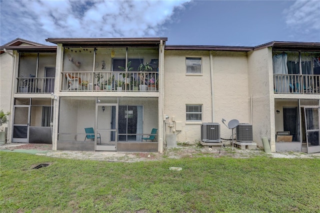 8440 Old Post Rd Unit 104, Port Richey, FL 34668 - back of property with stucco siding, a sunroom, and a lawn