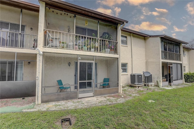 8440 Old Post Rd Unit 104, Port Richey, FL 34668 - back of house featuring a sunroom, stucco siding, a lawn, and a balcony