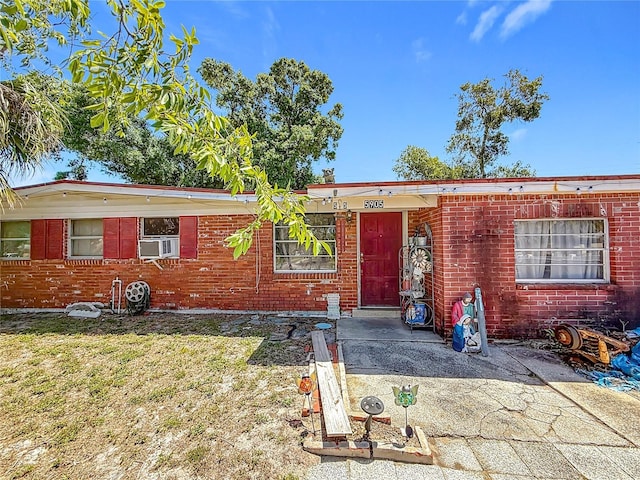 ranch-style home with brick siding, a front lawn, and cooling unit