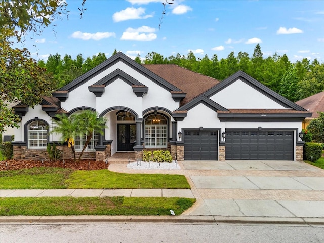 15045 Wind Whisper Dr, Odessa, FL 33556 - view of front of house with stucco siding, french doors, stone siding, an attached garage, and driveway