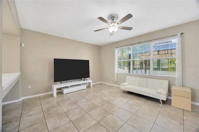 living area with light tile patterned floors, ceiling fan, and baseboards