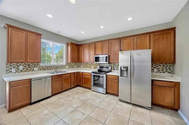 kitchen with tasteful backsplash, a sink, light countertops, appliances with stainless steel finishes, and brown cabinetry