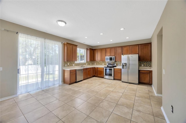 kitchen with tasteful backsplash, light countertops, brown cabinets, stainless steel appliances, and light tile patterned flooring