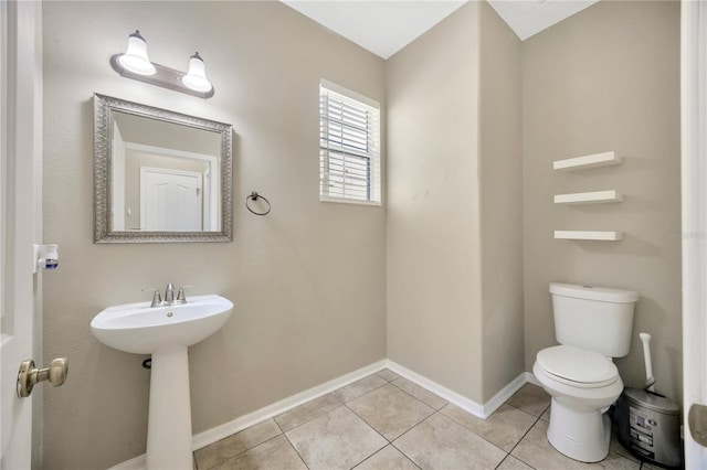 bathroom with tile patterned flooring, baseboards, and toilet