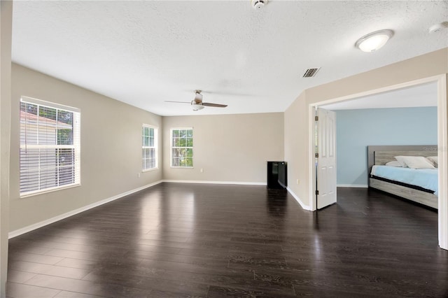 unfurnished living room featuring visible vents, a ceiling fan, wood finished floors, and a textured ceiling