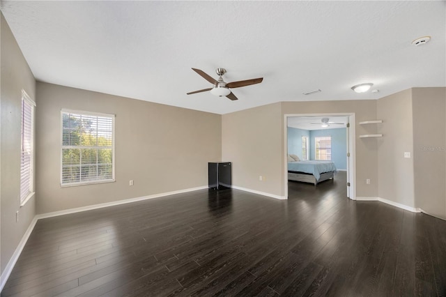 unfurnished living room with dark wood-style flooring, ceiling fan, and baseboards