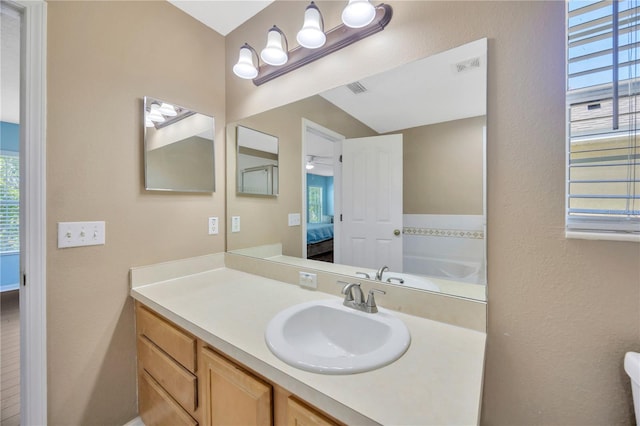 ensuite bathroom featuring vanity, ensuite bath, visible vents, and a textured wall