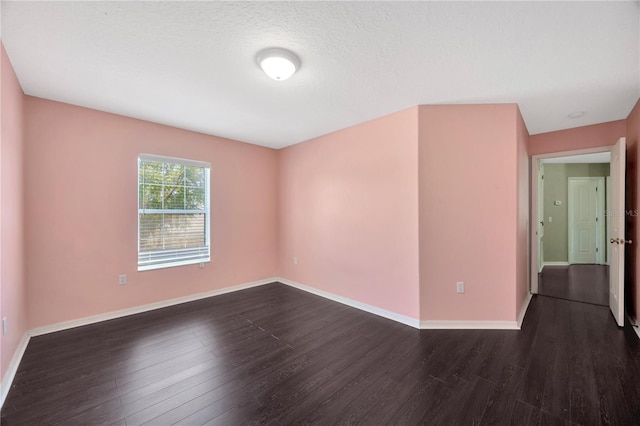 spare room with baseboards, a textured ceiling, and dark wood finished floors
