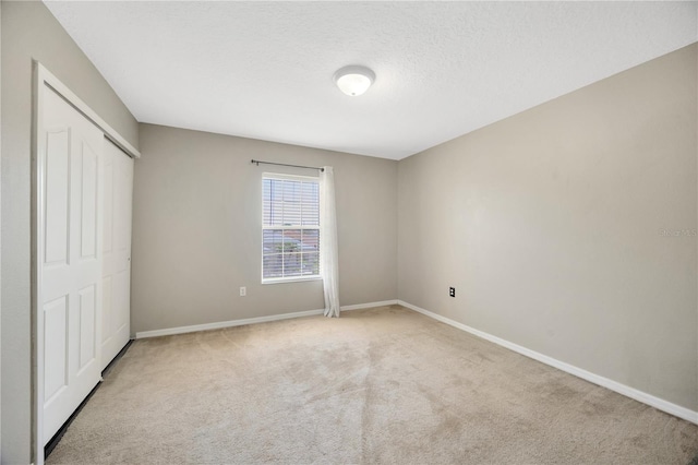 unfurnished bedroom with a textured ceiling, a closet, baseboards, and carpet floors