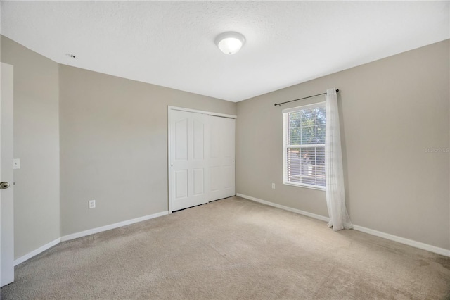 unfurnished bedroom with light carpet, baseboards, and a closet