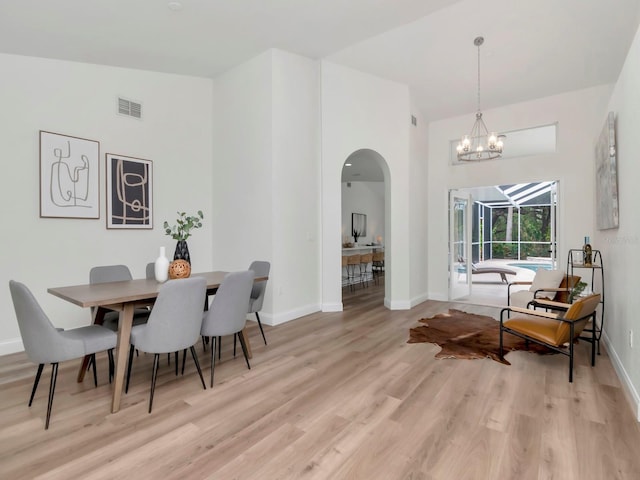 3728 Cypress Meadows Rd, Tampa, FL 33624 - dining room with arched walkways, light wood finished floors, baseboards, a towering ceiling, and a chandelier