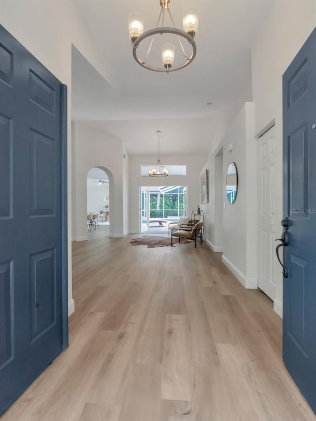 3728 Cypress Meadows Rd, Tampa, FL 33624 - entryway featuring a chandelier, arched walkways, light wood-style flooring, and baseboards