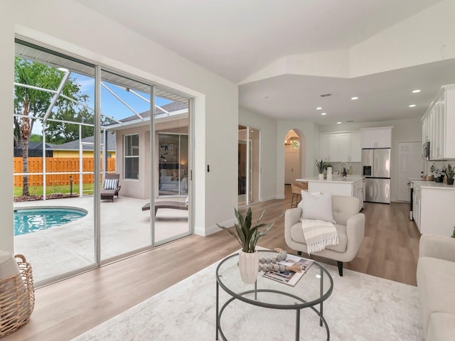 3728 Cypress Meadows Rd, Tampa, FL 33624 - living area with light wood-type flooring, arched walkways, recessed lighting, a sunroom, and lofted ceiling