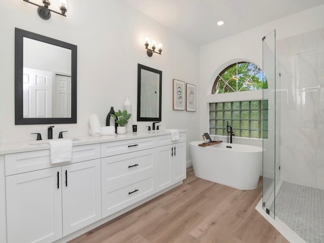 3728 Cypress Meadows Rd, Tampa, FL 33624 - bathroom with double vanity, a stall shower, a freestanding tub, wood finished floors, and recessed lighting