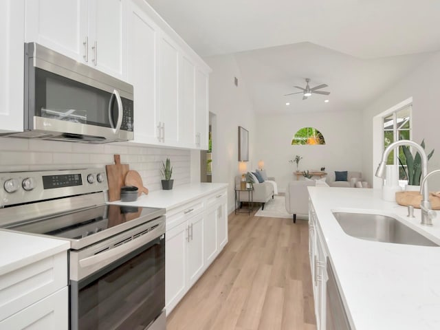 3728 Cypress Meadows Rd, Tampa, FL 33624 - kitchen featuring stainless steel appliances, a sink, backsplash, light wood-type flooring, and light countertops