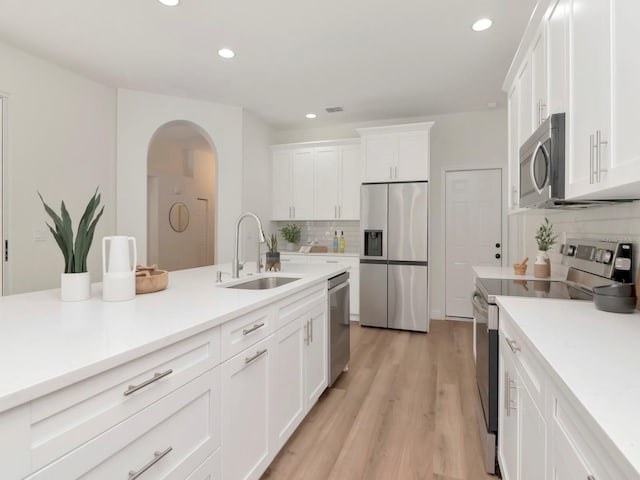 3728 Cypress Meadows Rd, Tampa, FL 33624 - kitchen featuring stainless steel appliances, a sink, arched walkways, backsplash, and white cabinetry