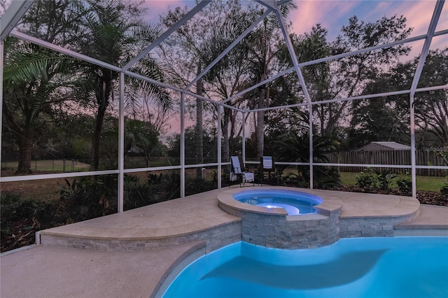 3728 Cypress Meadows Rd, Tampa, FL 33624 - pool at dusk with glass enclosure, a patio area, and a pool with connected hot tub