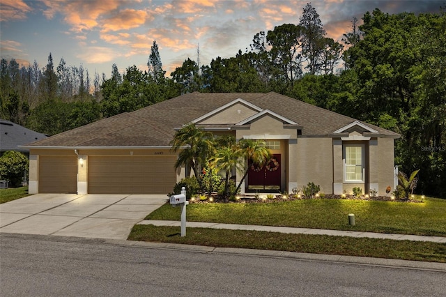 single story home with an attached garage, driveway, stucco siding, and a lawn