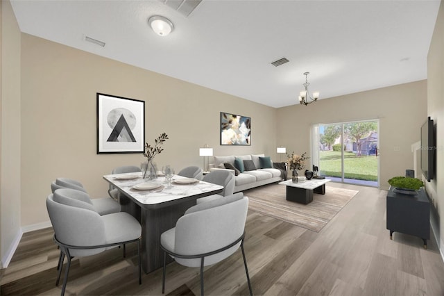 dining room featuring a notable chandelier, baseboards, visible vents, and wood finished floors