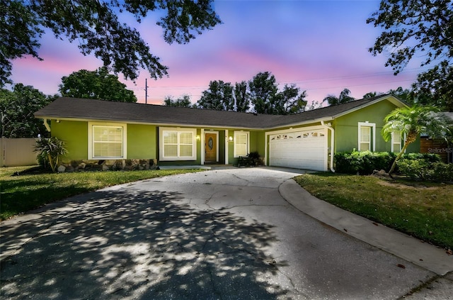 ranch-style house with concrete driveway, an attached garage, a front lawn, and stucco siding