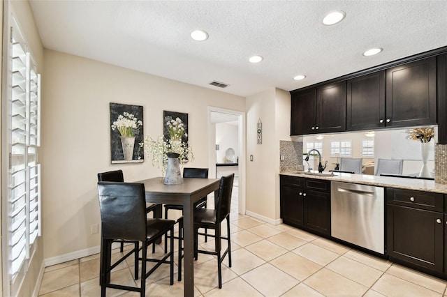 kitchen with visible vents, dishwasher, baseboards, a sink, and backsplash
