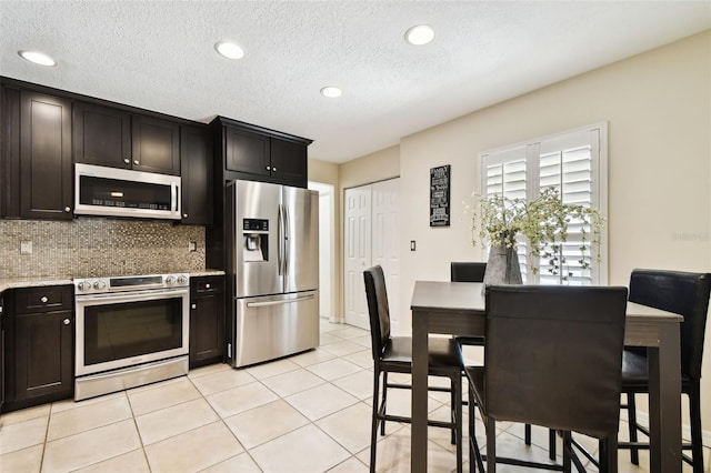 kitchen featuring light tile patterned flooring, recessed lighting, a textured ceiling, tasteful backsplash, and stainless steel appliances
