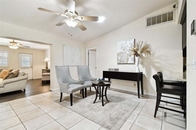 sitting room with visible vents, a ceiling fan, light tile patterned floors, and lofted ceiling