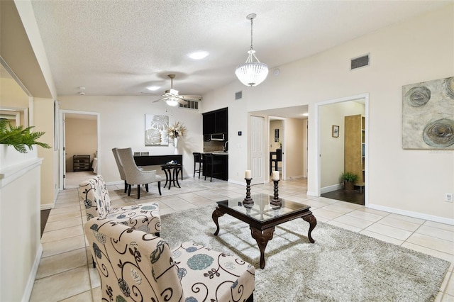 living area with light tile patterned floors, a ceiling fan, a textured ceiling, and visible vents