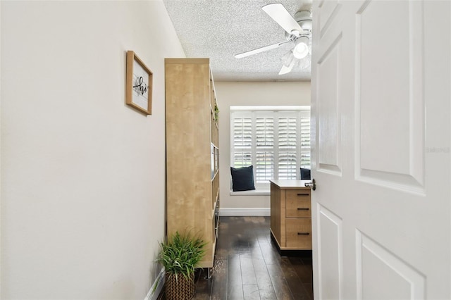 hall with a textured ceiling, baseboards, and dark wood-type flooring