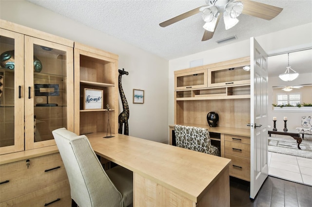 office area featuring visible vents, a ceiling fan, built in study area, and a textured ceiling