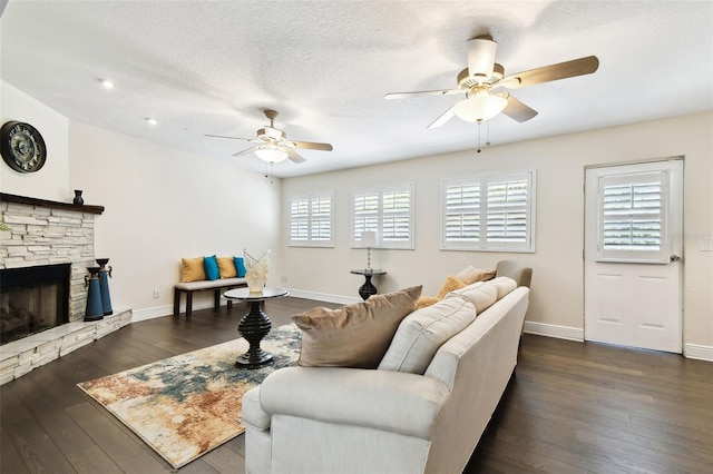 living area with a fireplace, a textured ceiling, dark wood finished floors, a ceiling fan, and baseboards