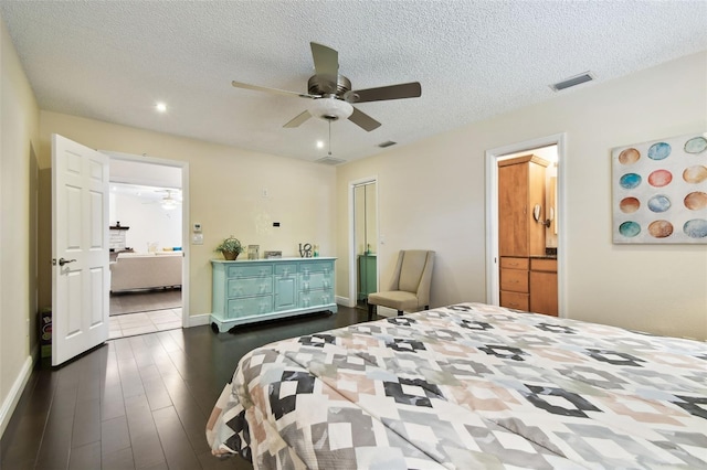 bedroom featuring visible vents, a textured ceiling, ensuite bathroom, and dark wood-style floors