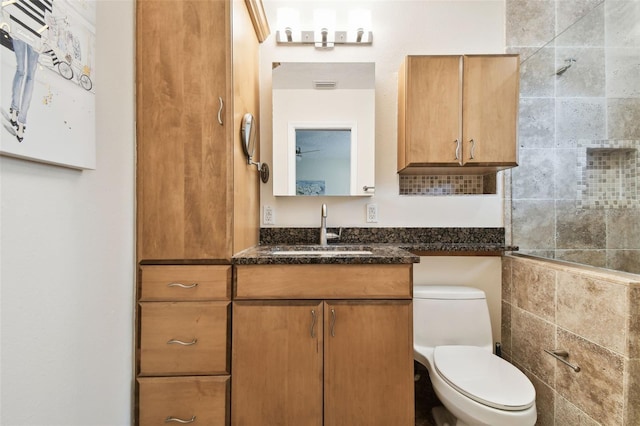 bathroom featuring toilet, visible vents, a tile shower, and vanity