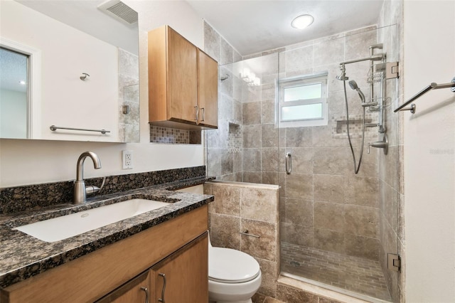 full bathroom featuring visible vents, vanity, toilet, tile walls, and a shower stall