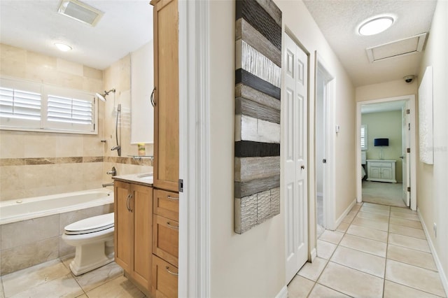 bathroom featuring visible vents, tile patterned floors, vanity, toilet, and tiled shower / bath combo