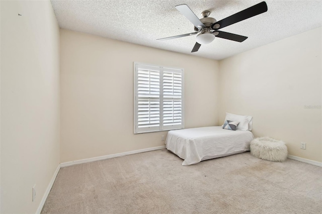 carpeted bedroom featuring baseboards, a ceiling fan, and a textured ceiling