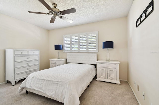 bedroom featuring baseboards, a textured ceiling, ceiling fan, and light carpet