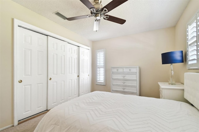 bedroom featuring multiple windows, a closet, a textured ceiling, and visible vents