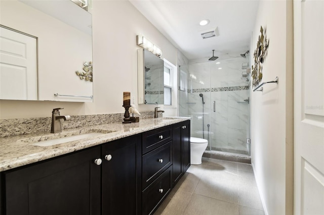 bathroom featuring tile patterned flooring, double vanity, toilet, a shower stall, and a sink
