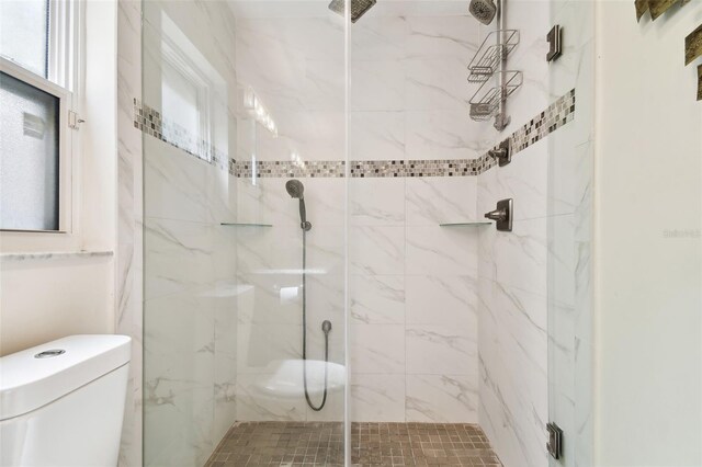 bathroom with a marble finish shower and toilet