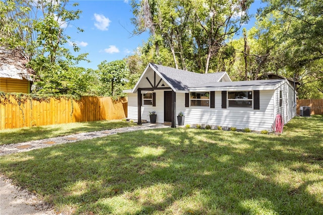 view of front of property with central air condition unit, a front yard, and fence