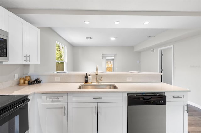 kitchen featuring a peninsula, light countertops, white cabinets, stainless steel dishwasher, and a sink