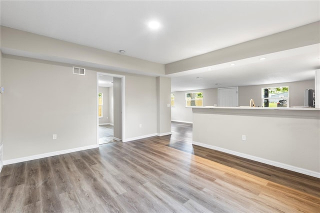 unfurnished living room with wood finished floors, baseboards, visible vents, and recessed lighting