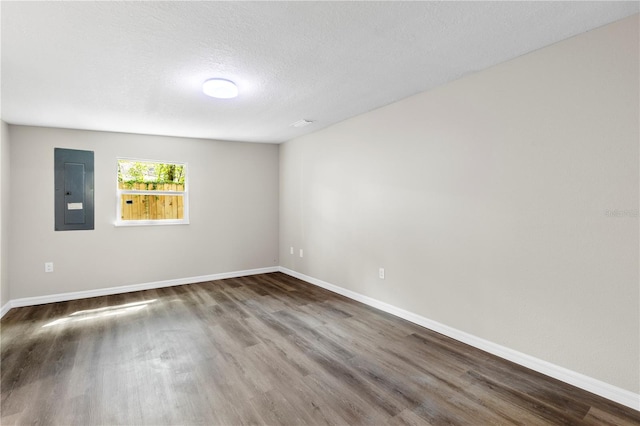 empty room featuring electric panel, baseboards, a textured ceiling, and wood finished floors