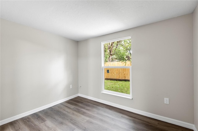empty room with baseboards, a textured ceiling, and wood finished floors