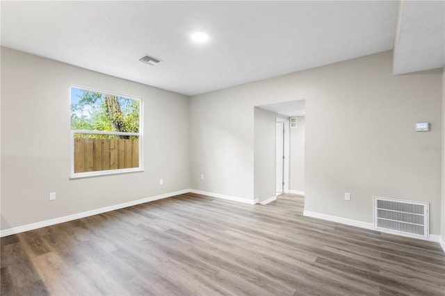 spare room with visible vents, baseboards, and wood finished floors