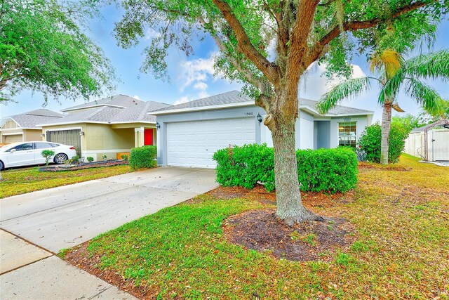 15410 Quail Woods Pl, Ruskin, FL 33573 - ranch-style home with an attached garage, driveway, stucco siding, and a front lawn